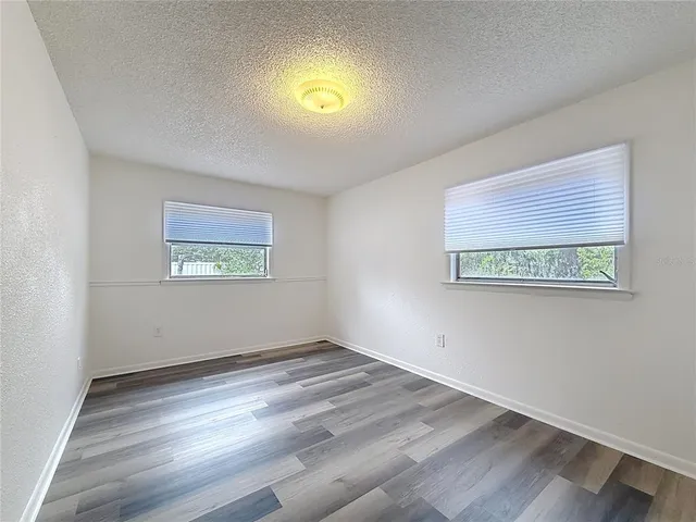 a view of empty room with wooden floor and windows