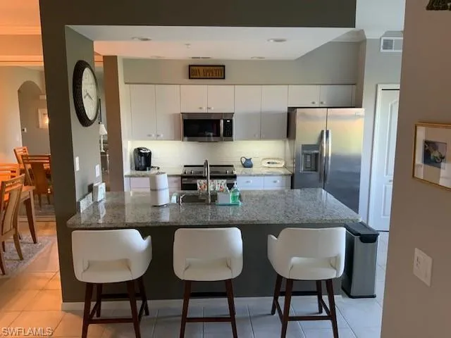 a kitchen with stainless steel appliances granite countertop a table chairs sink and cabinets