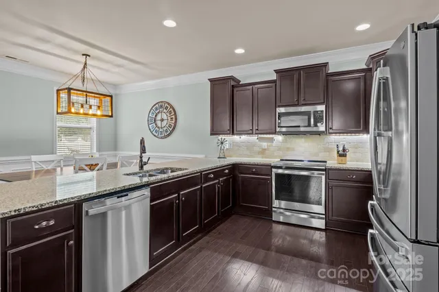 a kitchen with stainless steel appliances granite countertop a sink a stove a refrigerator and cabinets