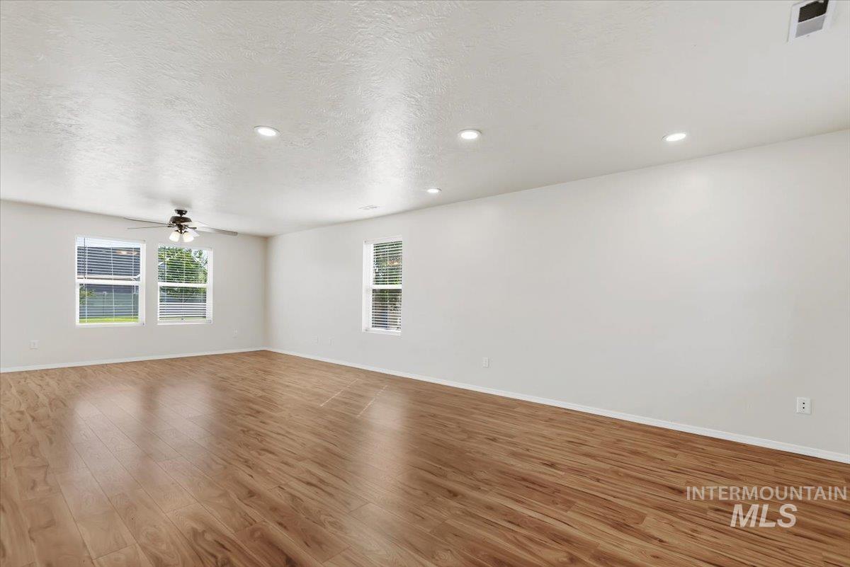 12310 West Hidden Point Drive Star, ID 83669 - Photo 29 of 48 Bright room featuring wood-finish flooring, recessed lighting, white walls, multiple windows with blinds, and a ceiling fan