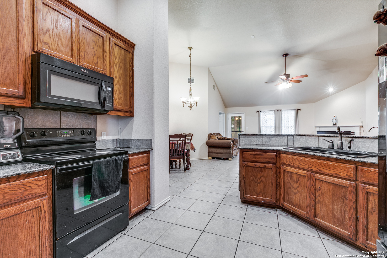 745 Cimarron Square Poteet, TX 78065 - Photo 13 of 33 a kitchen with stainless steel appliances granite countertop a stove top oven microwave and cabinets