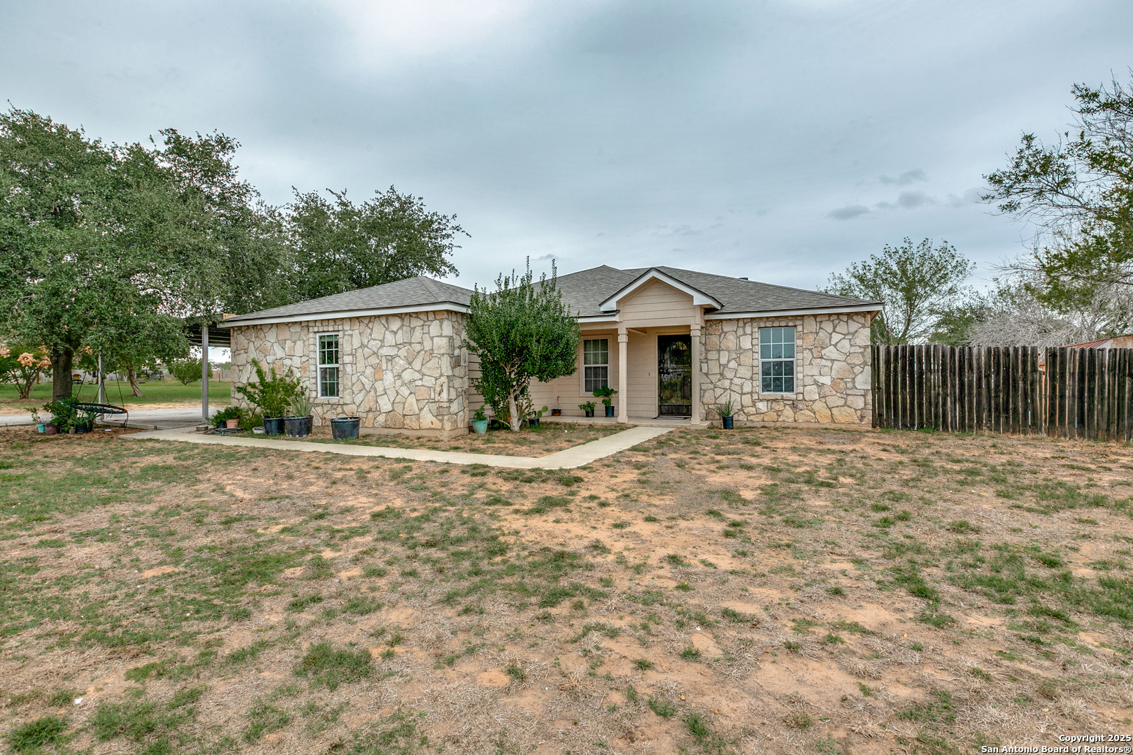 745 Cimarron Square Poteet, TX 78065 - Photo 4 of 33 a view of a white house with a yard and large tree