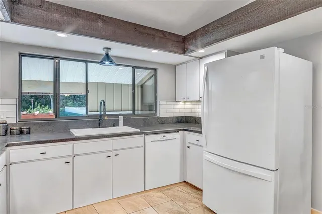 a kitchen with a sink a refrigerator a window and cabinets