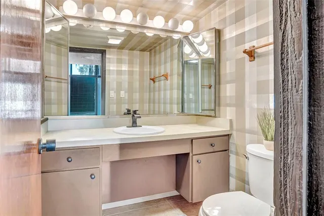 a bathroom with a sink and mirror with toilet