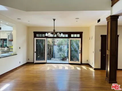 a view of an empty room with window and wooden floor