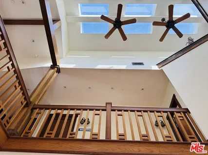 a view of staircase with lots of frames on wall and a ceiling fan