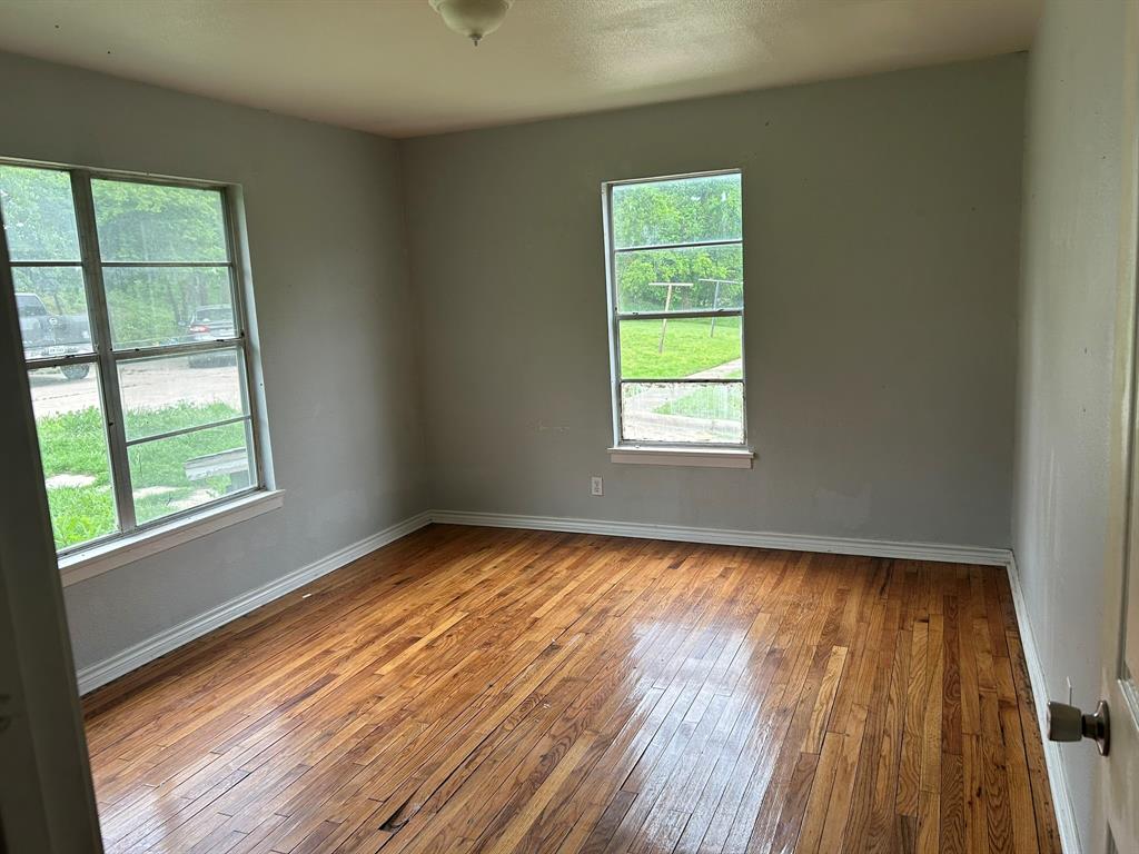 6 Pershing Drive Denison, TX 75020 - Photo 8 of 13 an empty room with wooden floor and windows