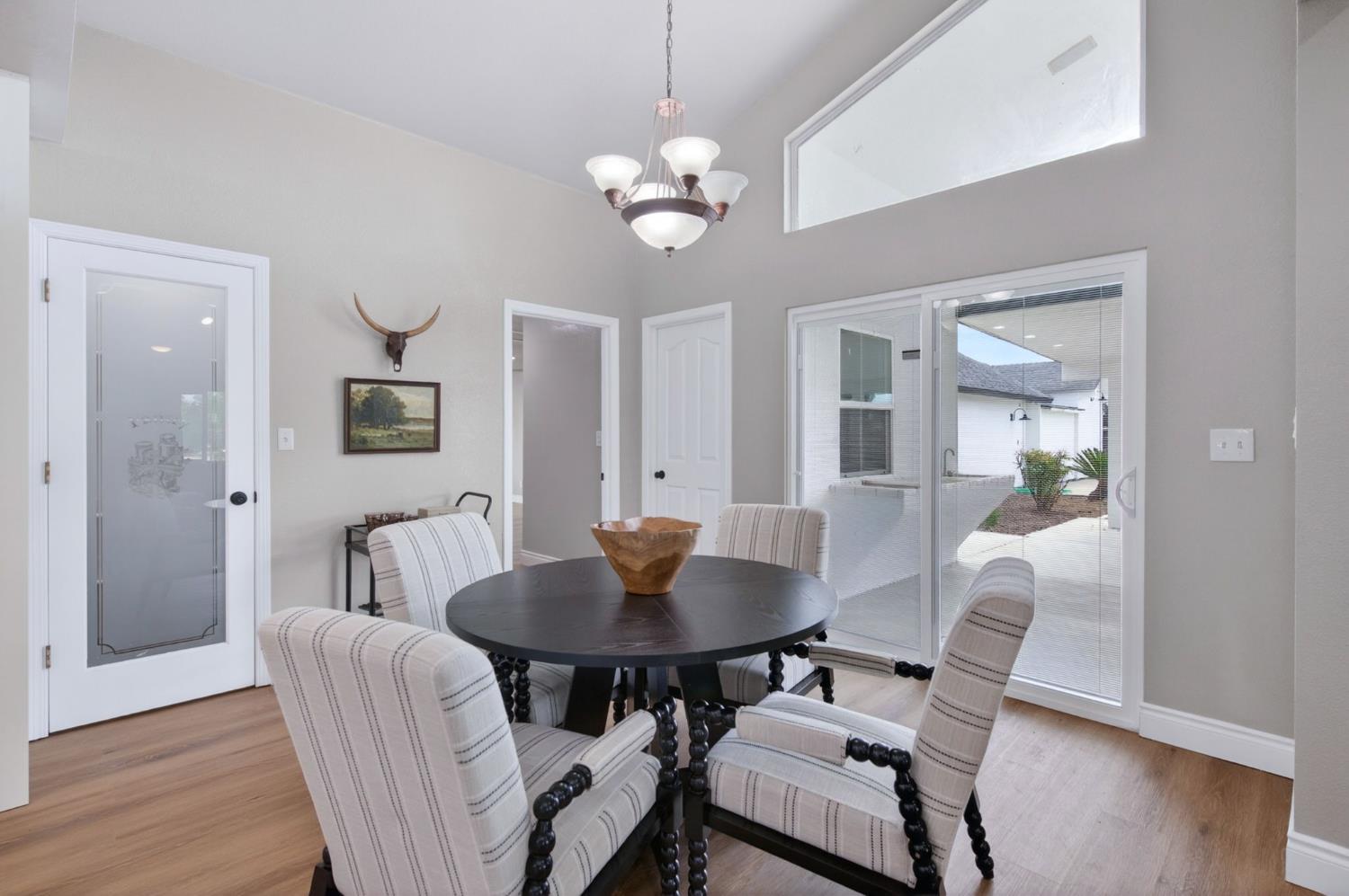16564 Monreal Road Madera, CA 93636 - Photo 19 of 59 a dining room with wooden floor a chandelier a glass table and chairs