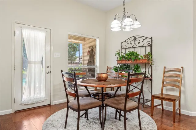 a dining room with wooden floor a chandelier a wooden table and chairs