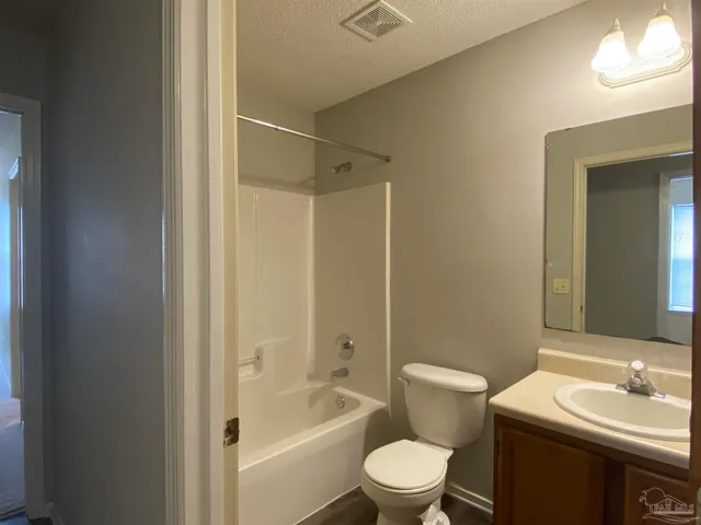 a backyard of a house with plants and large tree