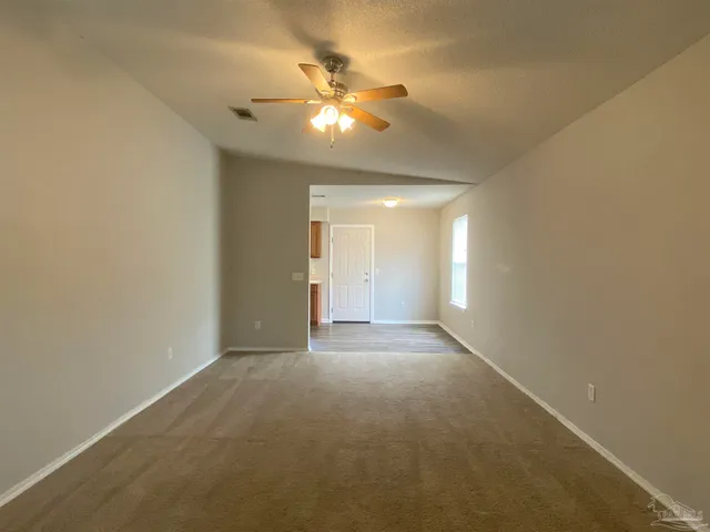 a view of an empty room with a chandelier fan