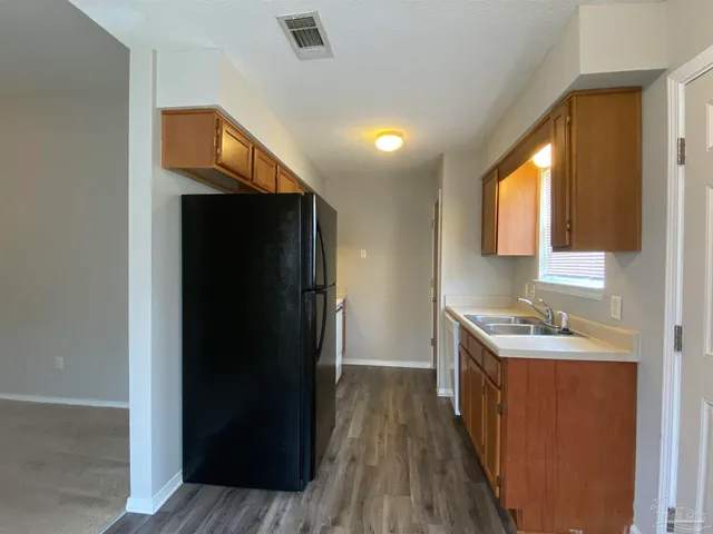 a kitchen with a sink a refrigerator and wooden floor