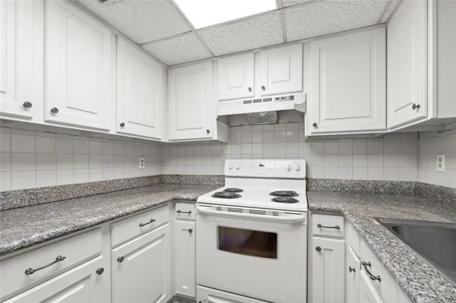 a kitchen with granite countertop white cabinets and white appliances