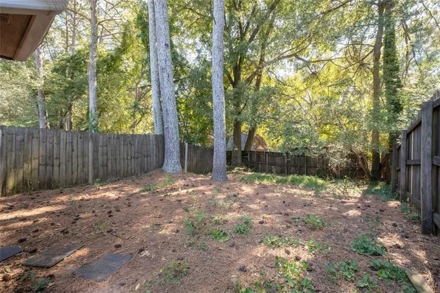 a backyard of a house with large trees and wooden fence