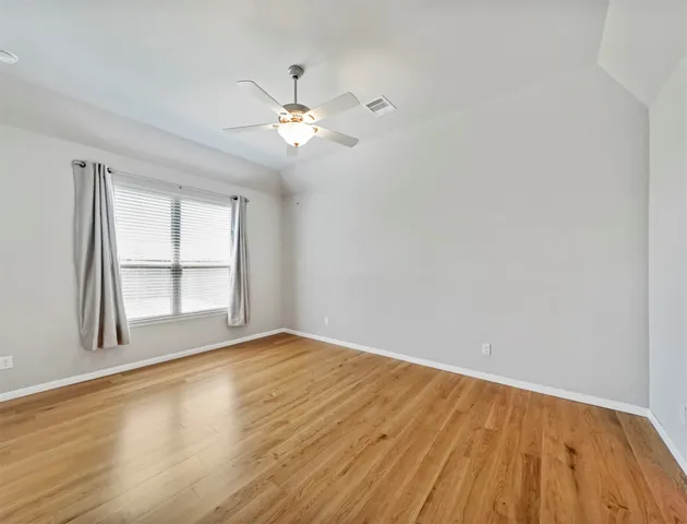 a view of empty room with wooden floor and fan