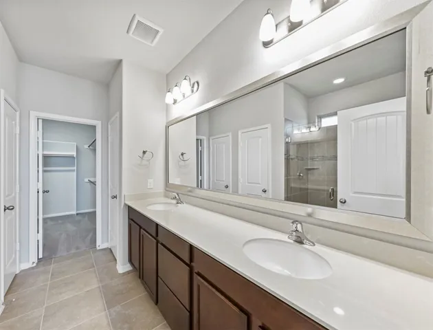 a bathroom with a sink double vanity granite tub shower and a mirror