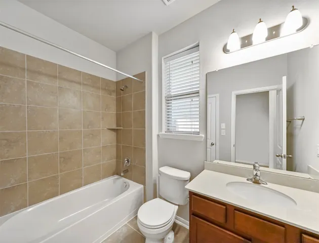 a bathroom with a sink a toilet a mirror a vanity and bathtub
