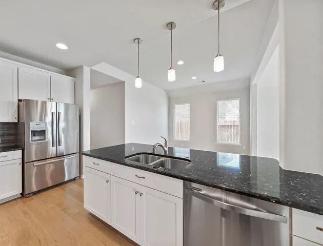 a kitchen with granite countertop a sink and stainless steel appliances