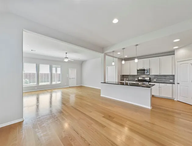 a view of large kitchen with granite countertop a large counter top stainless steel appliances and cabinets
