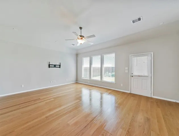 a view of an empty room with a window and wooden floor