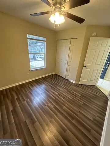 a view of an empty room with a window and wooden floor