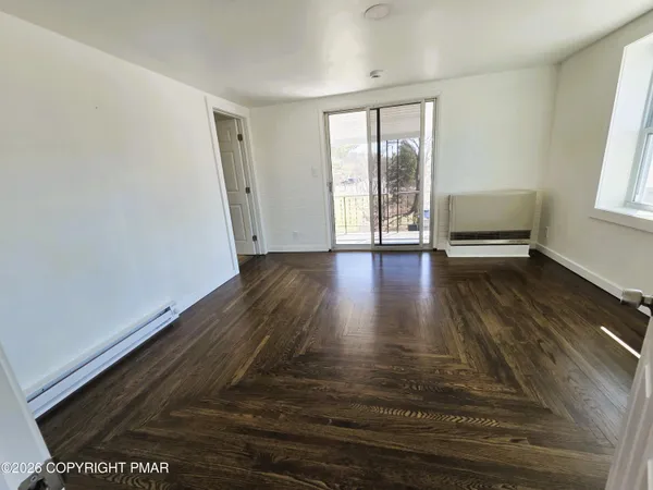 a view of an empty room with wooden floor and a window