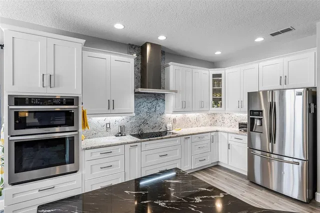 a kitchen with granite countertop white cabinets and stainless steel appliances
