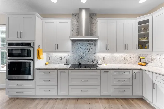a kitchen with granite countertop white cabinets and stainless steel appliances