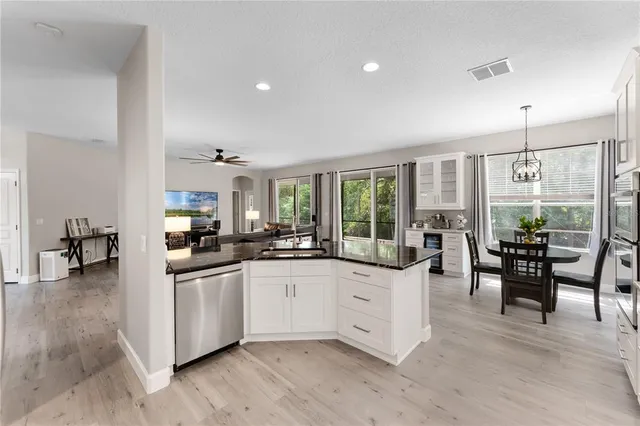 a large white kitchen with lots of counter space and chandelier