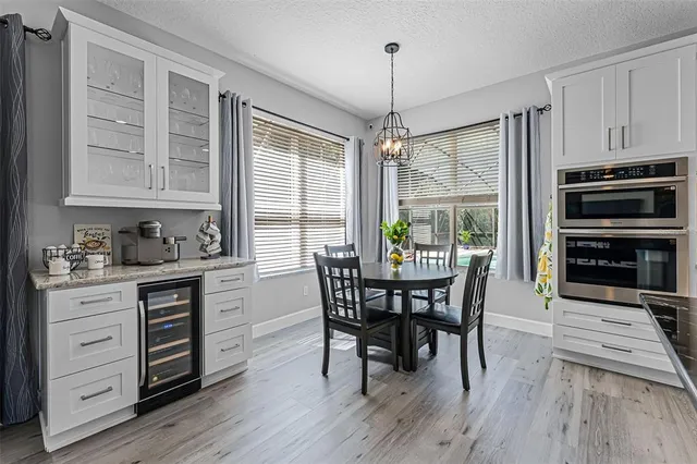a dining room with wooden floor a chandelier a wooden table and chairs