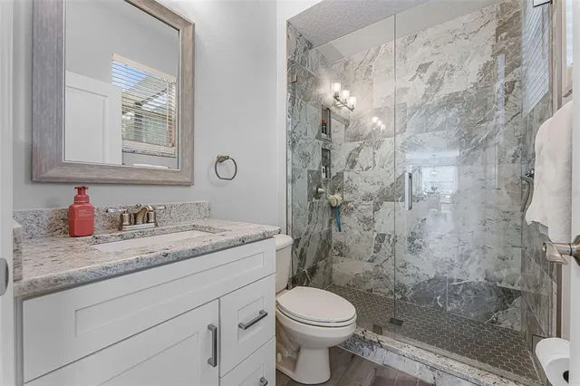 a bathroom with a granite countertop sink toilet a mirror and shower