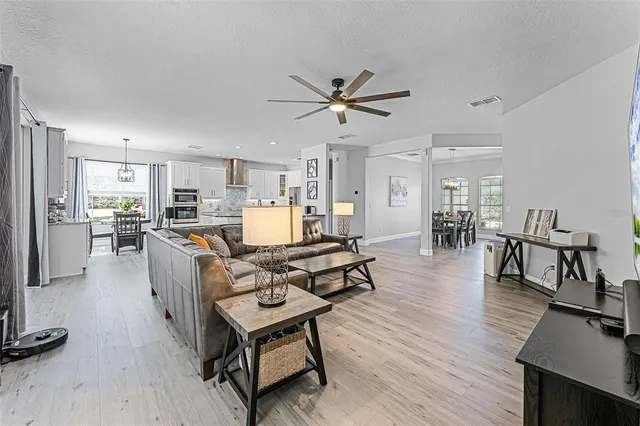 a living room with furniture and kitchen view with wooden floor