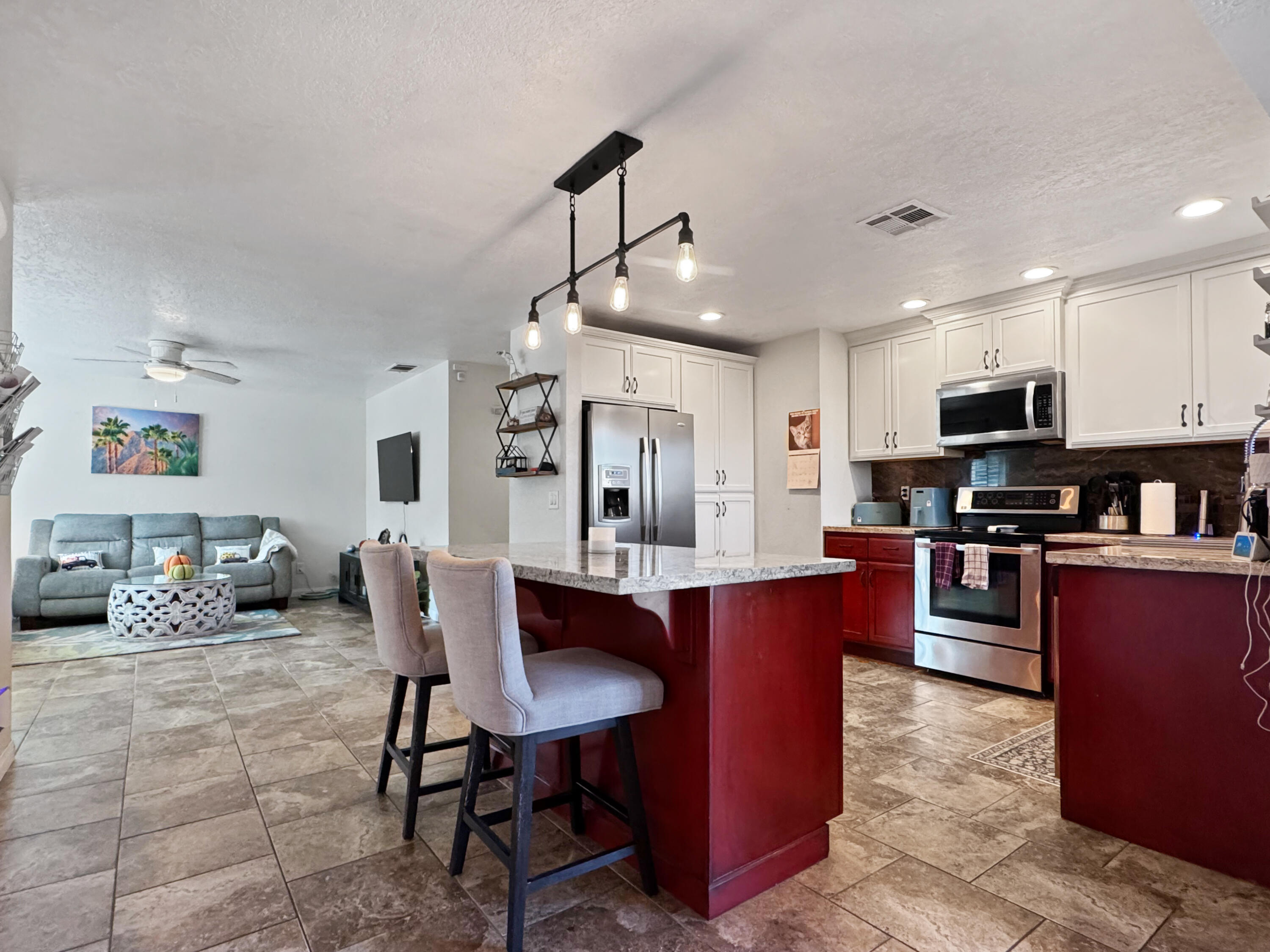53845 Avenida Herrera La Quinta, CA 92253 - Photo 8 of 25 a kitchen with stainless steel appliances kitchen island granite countertop a refrigerator a stove a sink a dining table and chairs with wooden floor