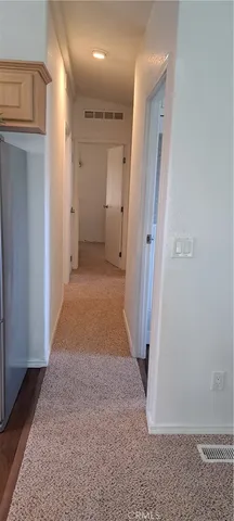 a view of a hallway with wooden floor and a refrigerator