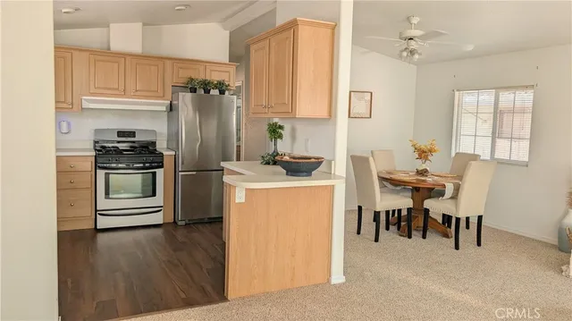 a kitchen with a refrigerator a stove cabinets dining table and chairs