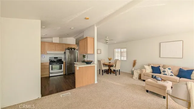 a living room with stainless steel appliances furniture a rug and a kitchen view