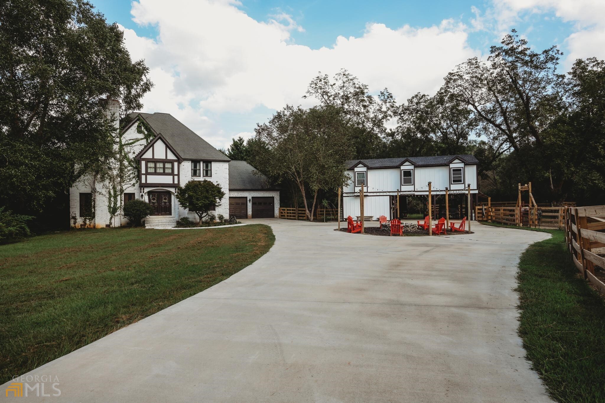 a view of a white house in front of a big yard with large trees