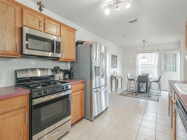 a kitchen with stainless steel appliances granite countertop a stove top oven a refrigerator a sink and white cabinets