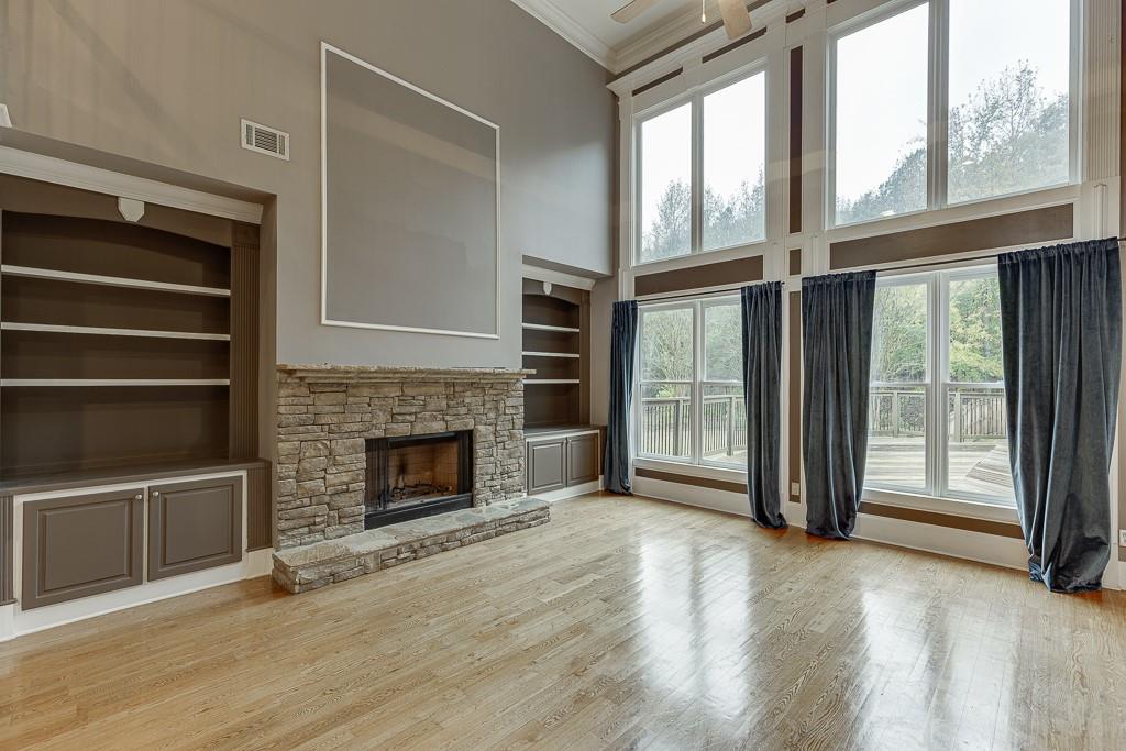 940 Chateau Forest Road Hoschton, GA 30548 - Photo 10 of 87 a view of an empty room with wooden floor fireplace and a window