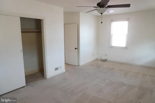 an empty room with a window and a ceiling fan
