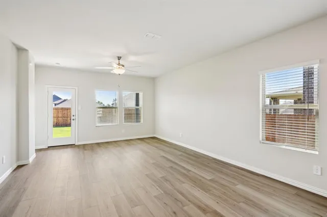 a view of an empty room with a window and wooden floor