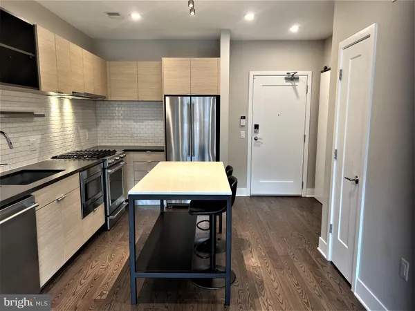 a kitchen with a refrigerator a sink and wooden floor