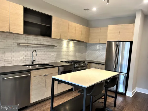 a kitchen with stainless steel appliances a table chairs in it and wooden floors