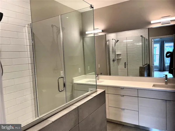 a bathroom with a tub shower sink and mirror