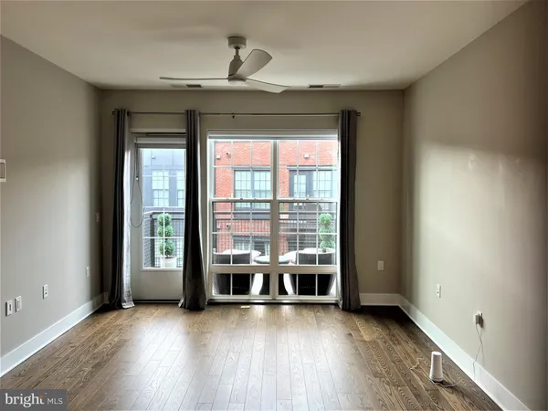 a view of an empty room with wooden floor and a window