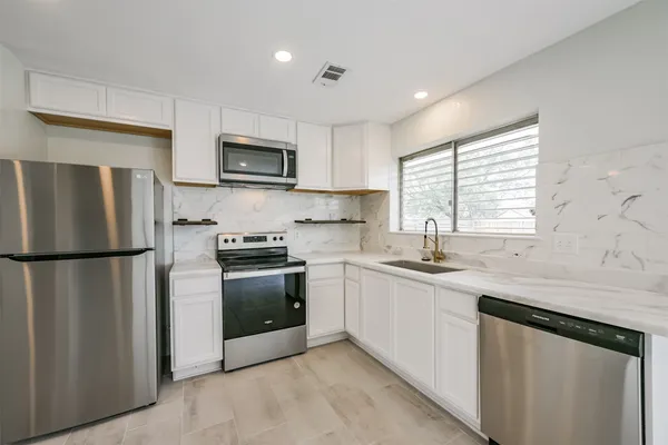a large kitchen with stainless steel appliances granite countertop a sink and a stove