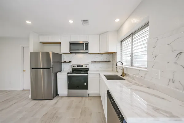 a kitchen with granite countertop a refrigerator stove top oven and sink