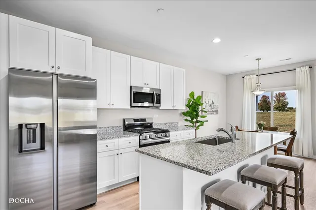 a kitchen with stainless steel appliances granite countertop a sink a stove and a refrigerator