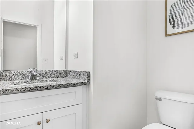 a bathroom with a granite countertop sink and a toilet
