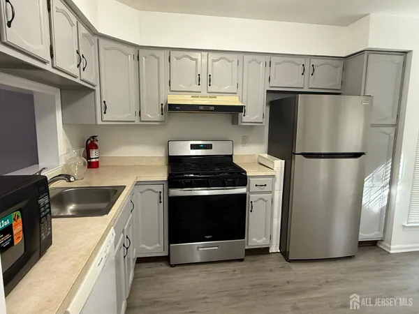 a kitchen with stainless steel appliances granite countertop a refrigerator a stove a sink and a microwave